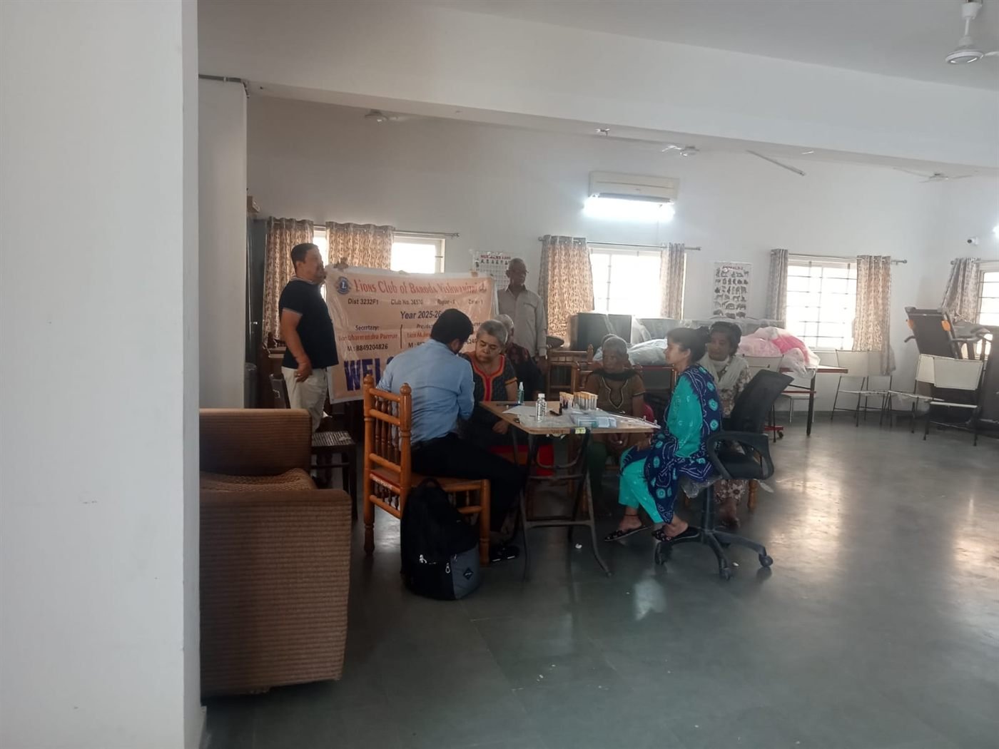 A community meeting with families seated in the Seva Tirth hall